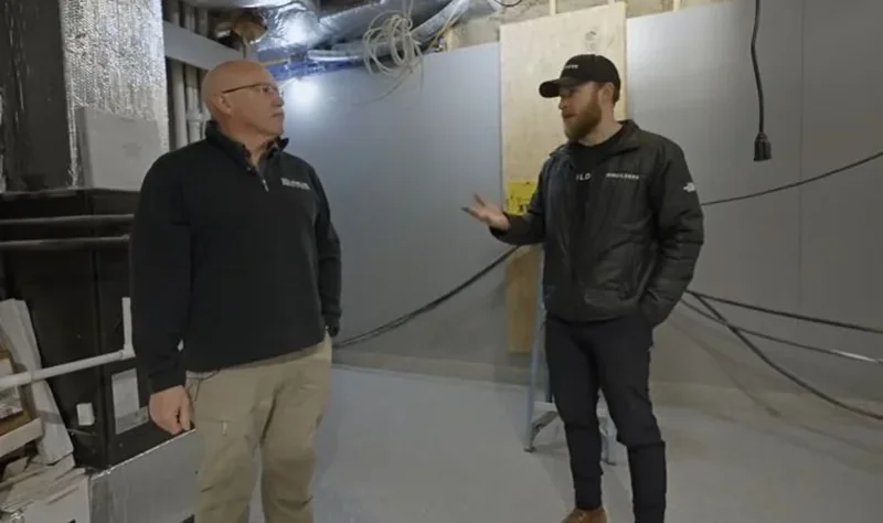 Plumber talking through a plumbing plan with a homeowner in a finished basement