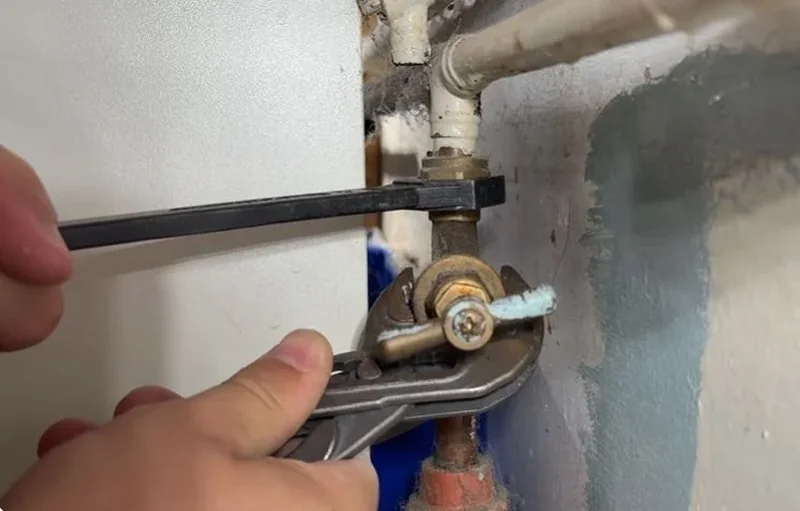 Plumber tightening a brass shutoff valve with an adjustable wrench