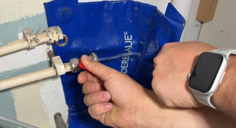 Plumber’s hands working on a pipe fitting at a water supply connection
